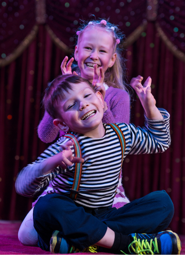 boy and girl laughing making funny poses in a theatre